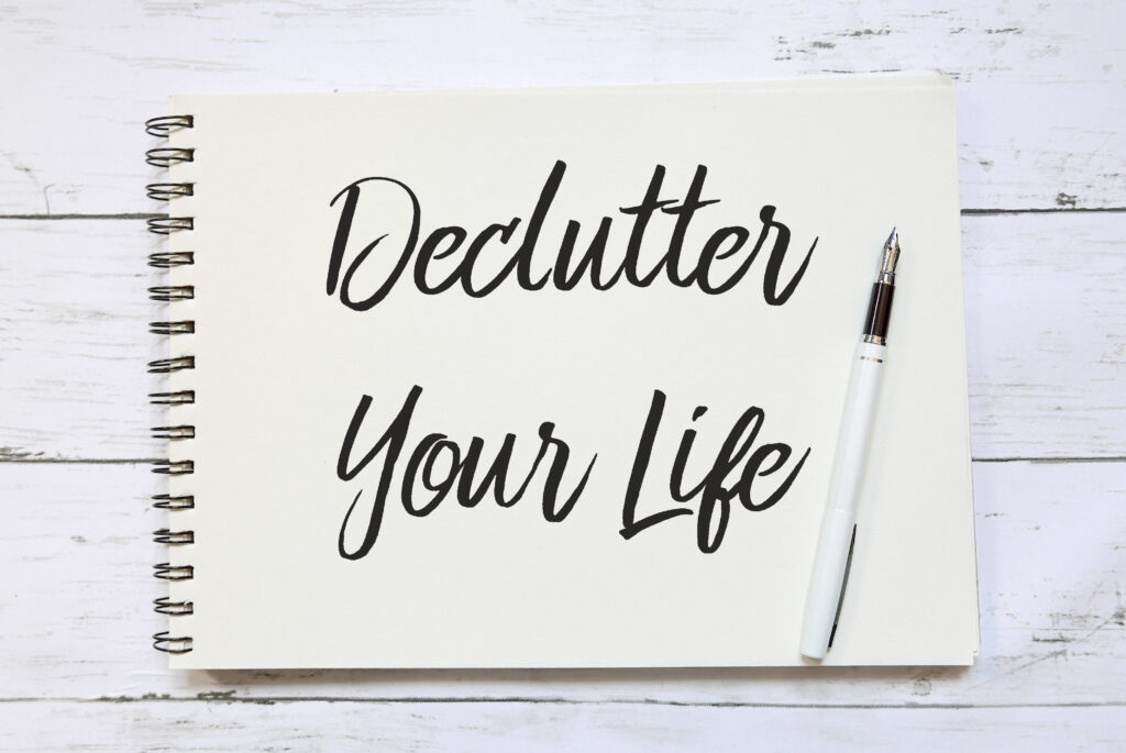 Top view of pen and notebook written with Declutter Your Life on wooden background.