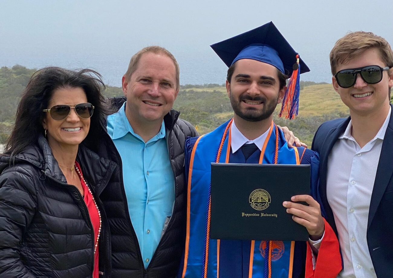 Steph, her two sons and husband, smiling at the camera on her son's graduation day